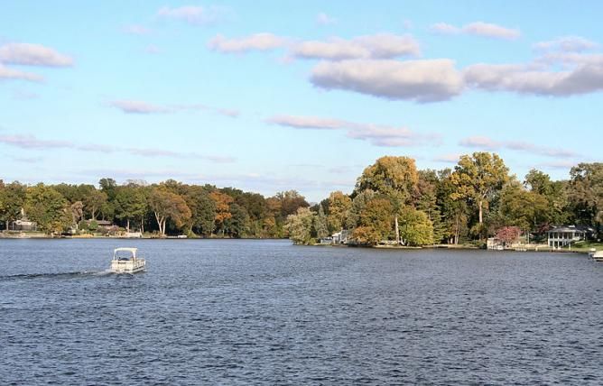 a boat is traveling on the water in front of some houses with trees around it