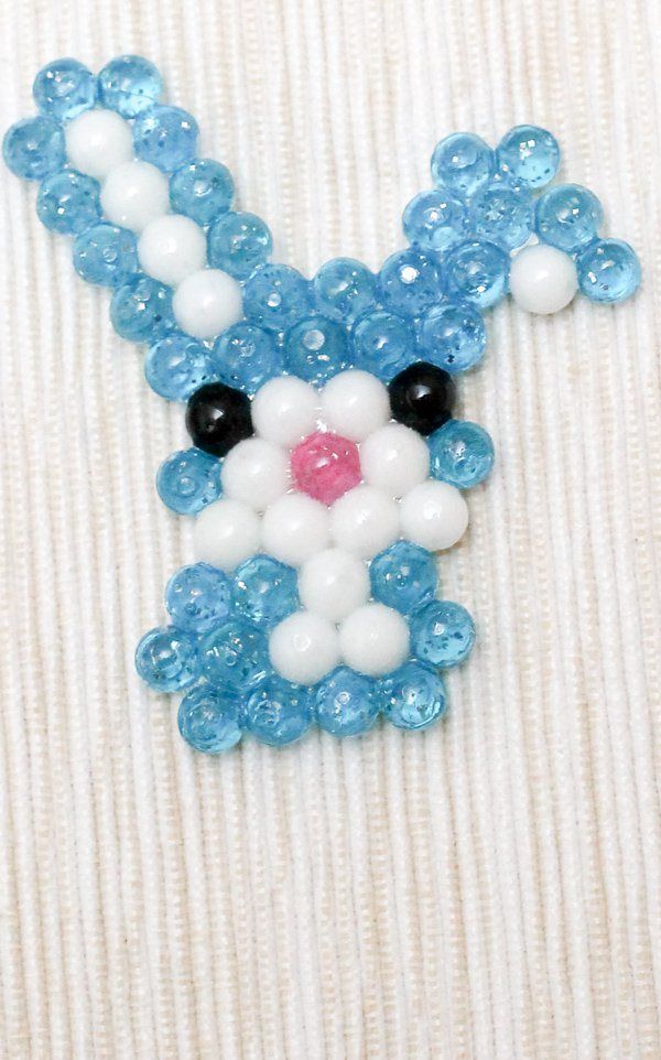 a blue and white bunny brooch sitting on top of a piece of fabric with beads