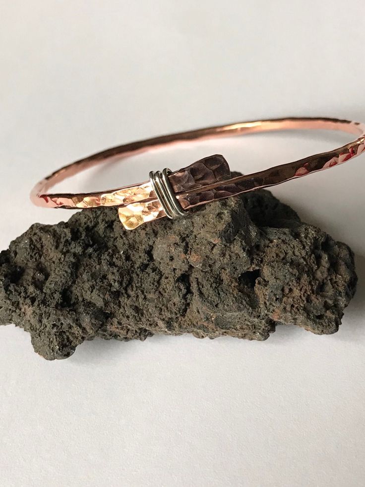 Rustic yet pretty copper bangle with a sterling silver detail The bangle is made of 2.6 mm copper wire, the ends was flatten and tied with sterling silver wire, then soldered (bangle is not adjustable).  This bangle will look good on its own, in combination with other bangles and can be worn by women and men, which is made it as a perfect gift for 7th wedding Anniversary for her or for him. It can be made in different sizes, so what if both of you would have matching bangles? Please choose size by the internal diameter.  The bangle is not covered with any lacquer, so it has all the copper's benefits.  For more versatile bangle please check out my shop www.leofwinejewellery.etsy.com Hammered Copper Bangle Bracelets, Hammered Copper Bangle Bracelet, Adjustable Hammered Rose Gold Bangle, Rose Gold Copper Bangle As Gift, Rose Gold Sterling Silver Bangle Bracelet, Hand Wrapped Silver Copper Bangle, Hammered Rose Gold Bangle, Elegant Hand Wrapped Copper Bangle, Hammered Copper Jewelry