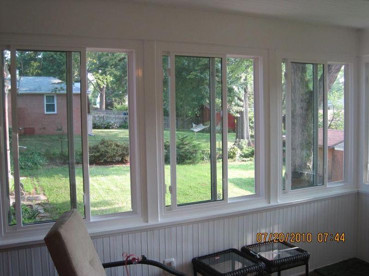 a living room filled with lots of windows next to a table and chair in front of a window