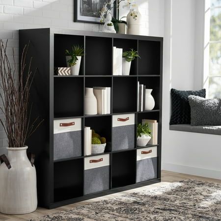 a black bookcase filled with lots of different types of storage bins and plants