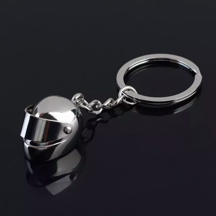 a metal bell shaped keychain on a black surface with a silver ball hanging from it's side