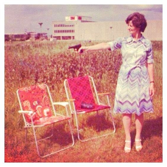 an older woman pointing at two lawn chairs in a field with a building in the background