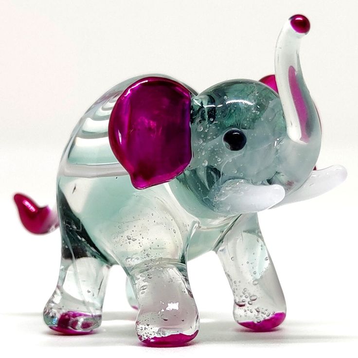 a glass elephant figurine with pink ears and tusks