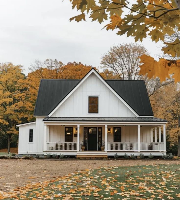 a white house with black roof in the fall