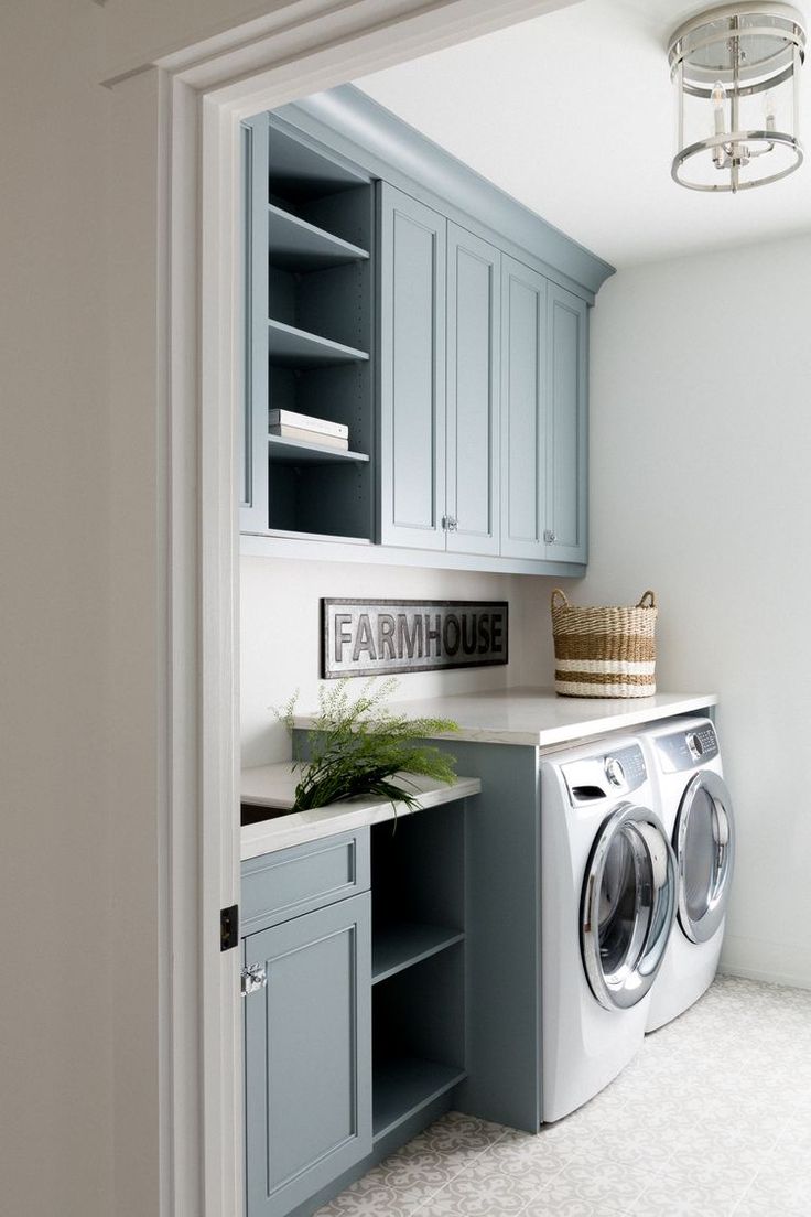 a washer and dryer in a laundry room with blue cupboards on the wall