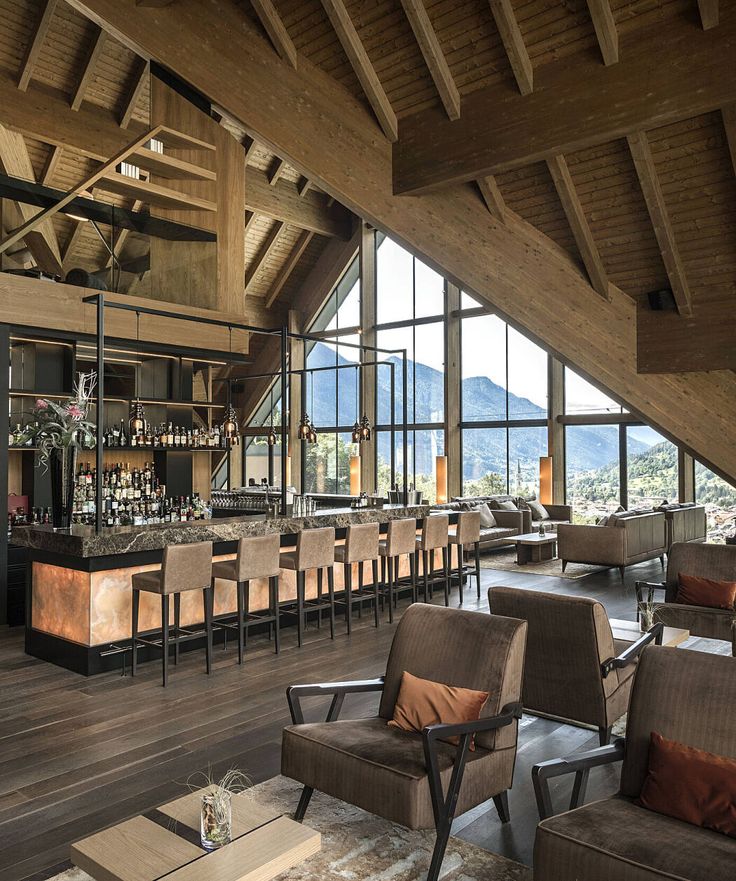 a bar with lots of chairs in front of large windows and mountain view behind it