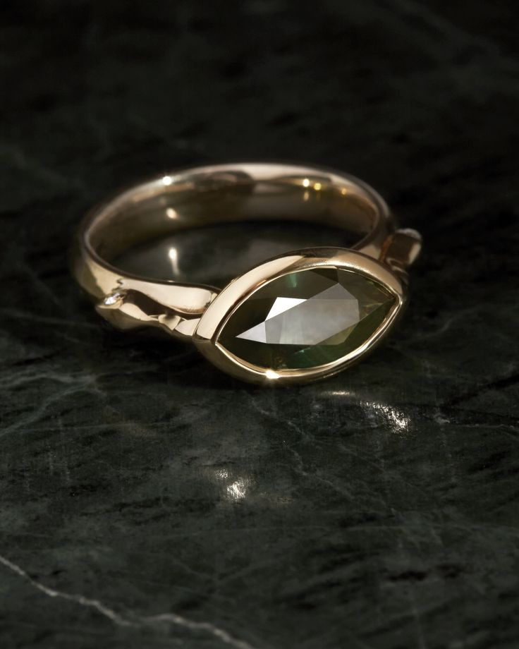 a close up of a ring on a black surface with a stone in the middle