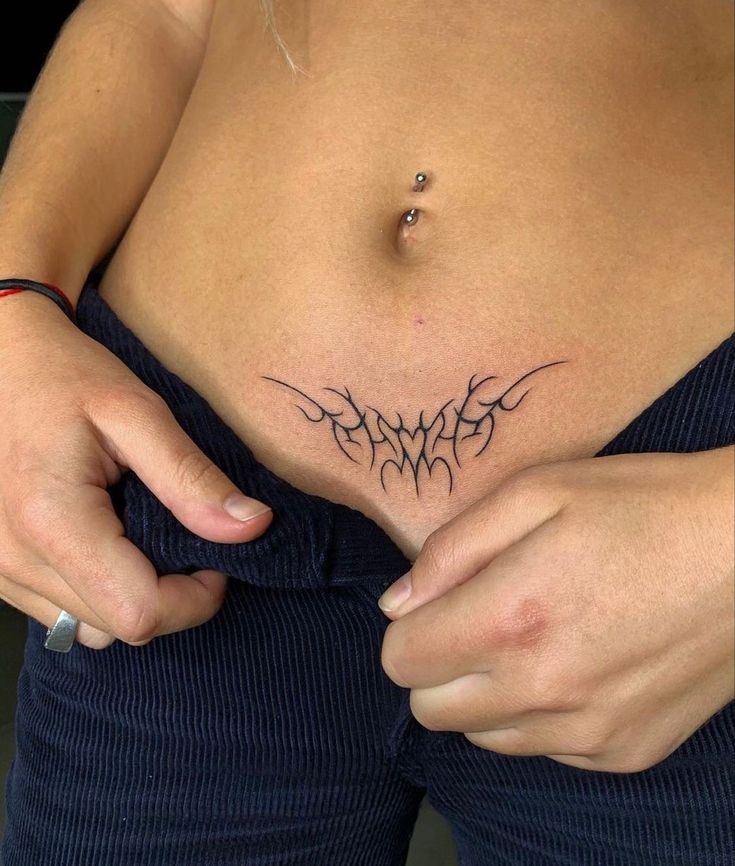 a woman is showing off her stomach tattoo