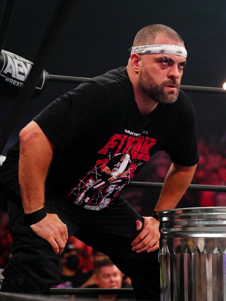 a man with a blindfold on his head standing next to a metal trash can