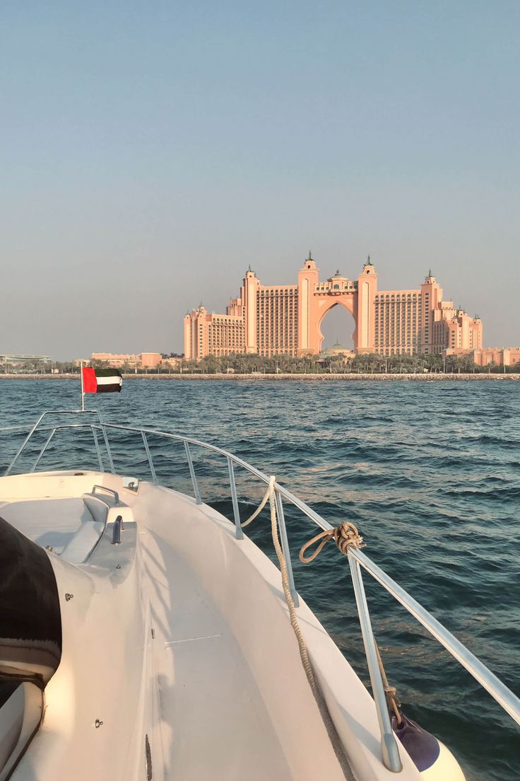 a boat traveling on the water in front of a large building