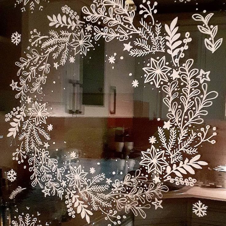 a frosted glass window with white snowflakes and leaves on the outside, in front of a kitchen counter