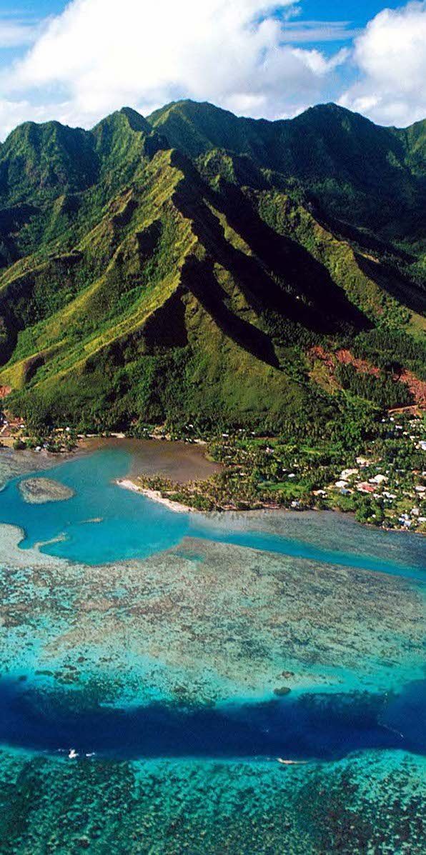 an aerial view of the ocean with mountains in the background