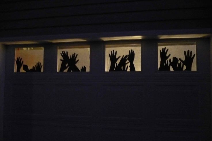 silhouettes of hands reaching up out of a garage door