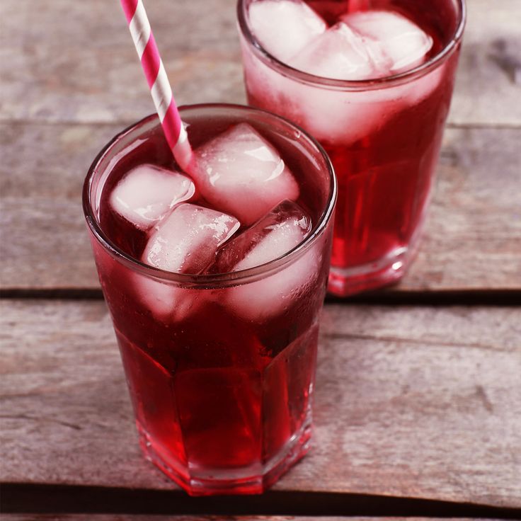 two glasses filled with ice sitting on top of a wooden table