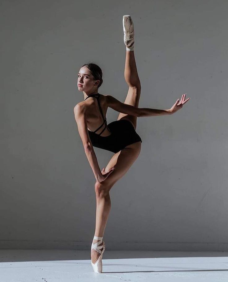 a woman in a black leotard and ballet shoes is doing a dance pose