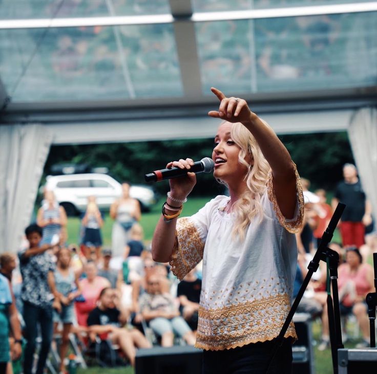 a woman standing on top of a stage holding a microphone in front of an audience