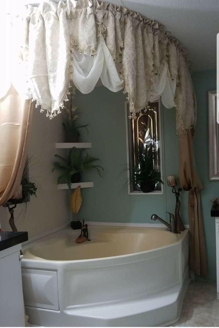 a bath tub sitting under a window next to a sink in a room with green walls