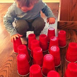 a toddler playing with red cups on the floor