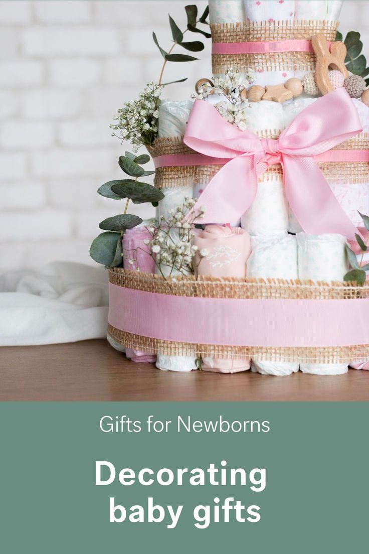 a baby shower cake with pink ribbon and teddy bears on top, in front of a brick wall