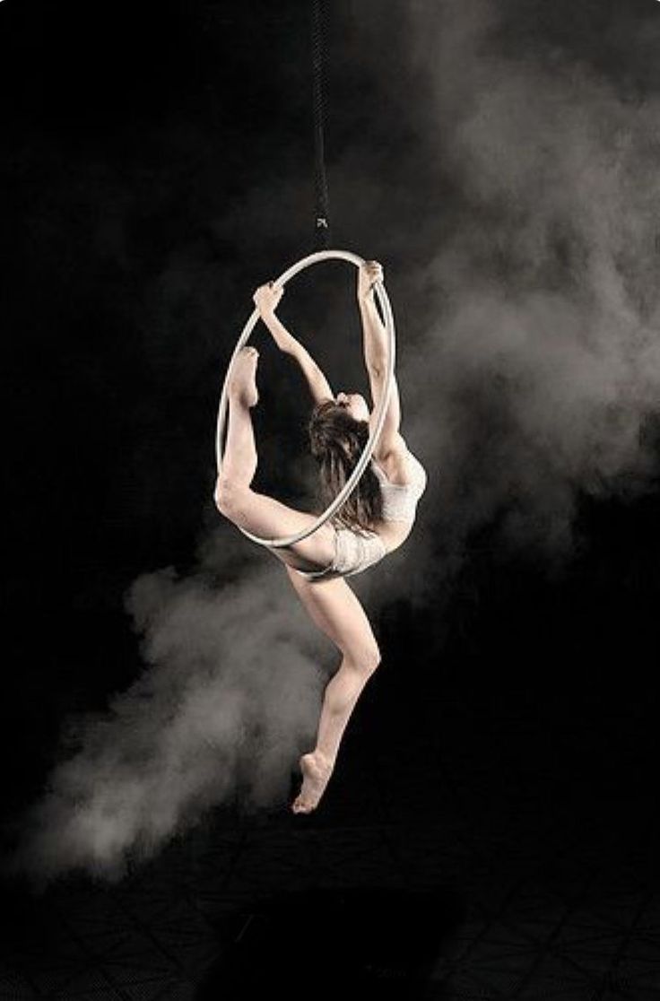 a woman is doing aerial acrobatics on a hoop