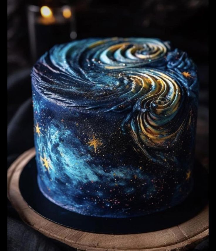 a blue cake with stars and swirls on it sitting on a wooden platter