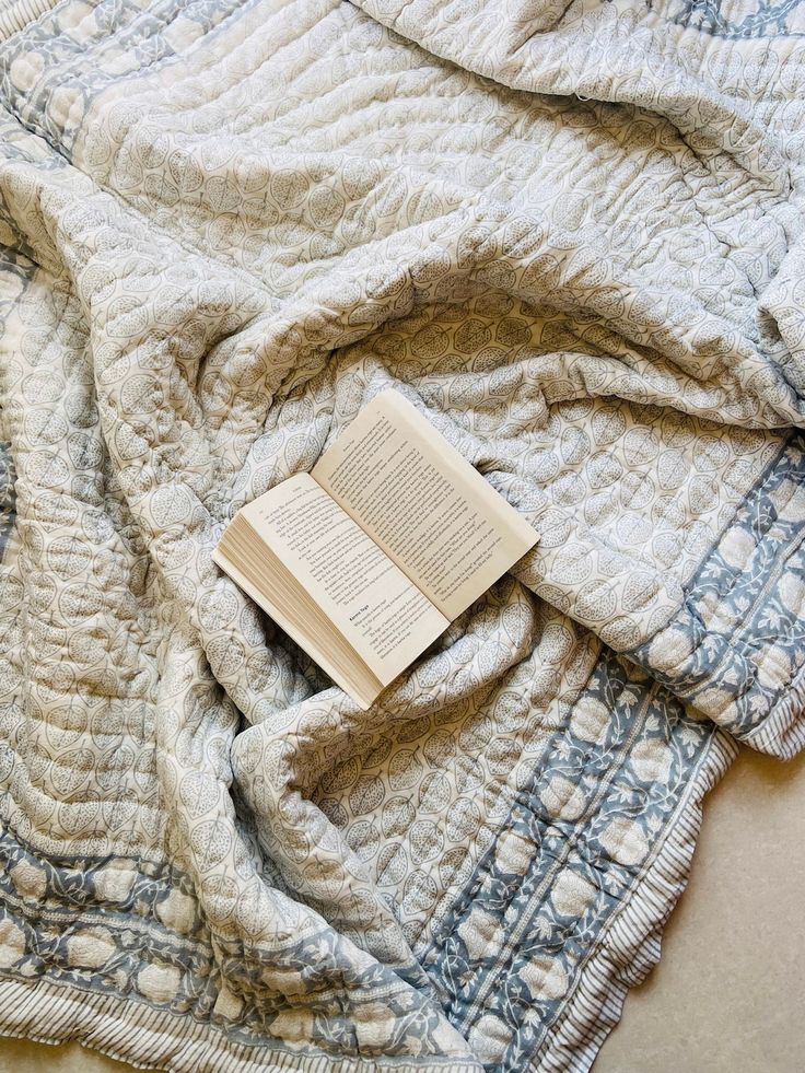 an open book laying on top of a blanket