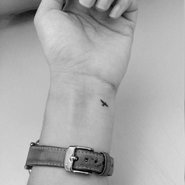 a woman's wrist with a small airplane tattoo on the left side of her arm