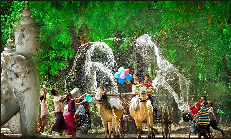 people are gathered around a fountain with water shooting from the top and horses standing in front