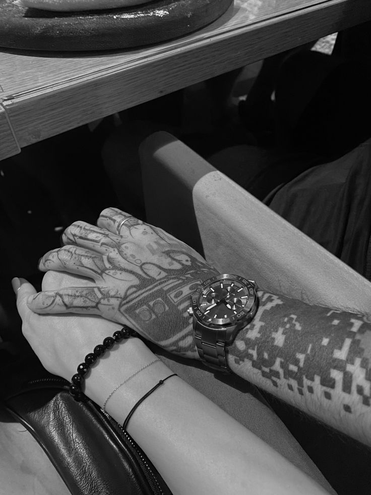 a person with tattoos on their arm sitting at a table