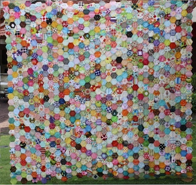 a large quilt made out of many different colored buttons on the front and back of it