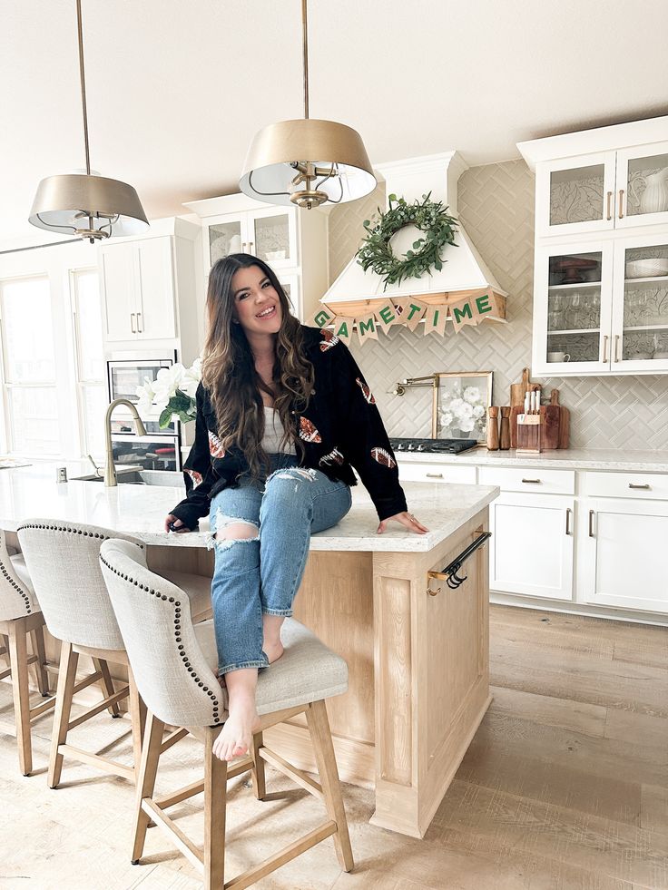 a woman sitting on top of a counter in a kitchen