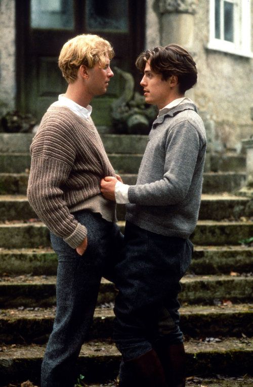 two young men standing next to each other in front of a stone building with steps