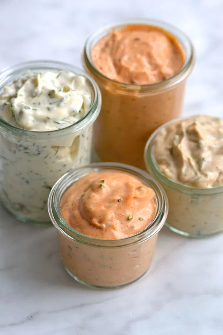 four jars filled with different types of dips