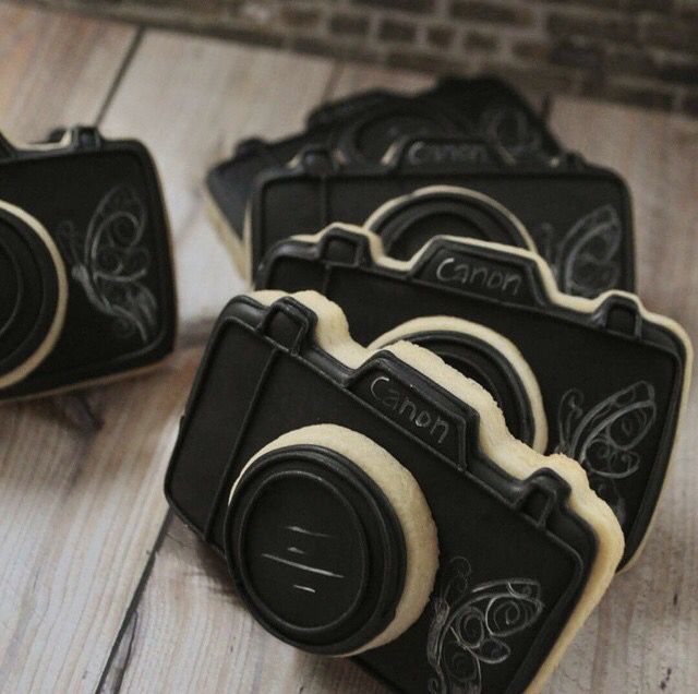 some cookies shaped like cameras on a wooden table