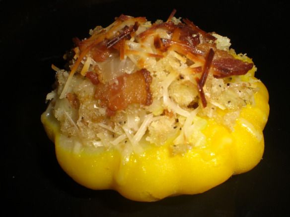 a yellow pepper covered in bacon and cheese on a black plate with other food items