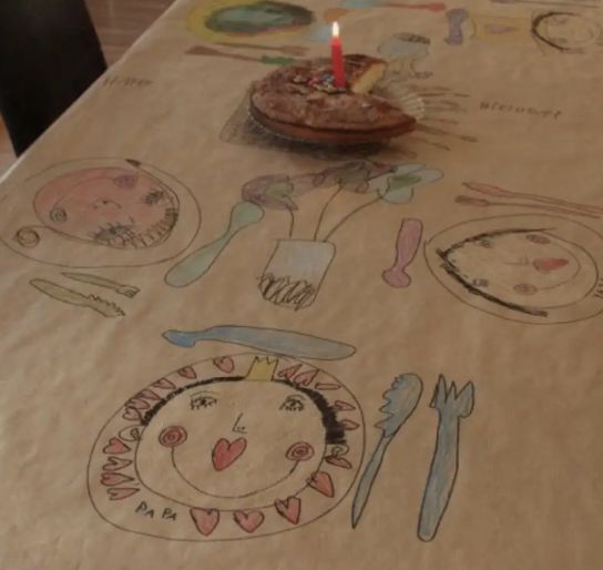 a table with a birthday cake on it and other items drawn on the table cloth