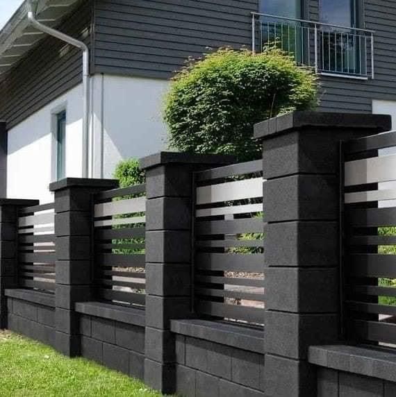 a black and white fence in front of a house with grass on the ground next to it