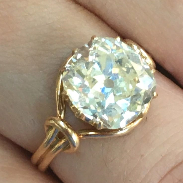 a close up of a person's hand holding a ring with a diamond in it