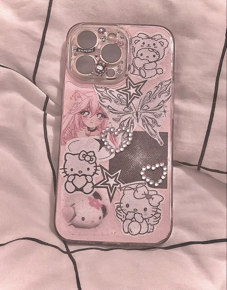 an iphone case with hello kitty stickers on the front and back cover, sitting on a bed