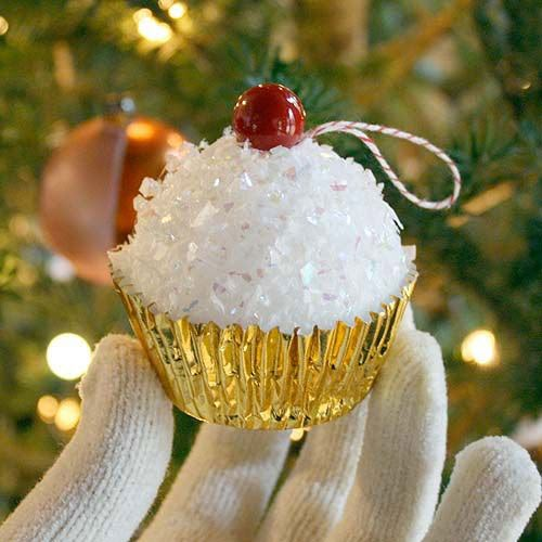 a cupcake ornament hanging from a christmas tree with white gloves on it