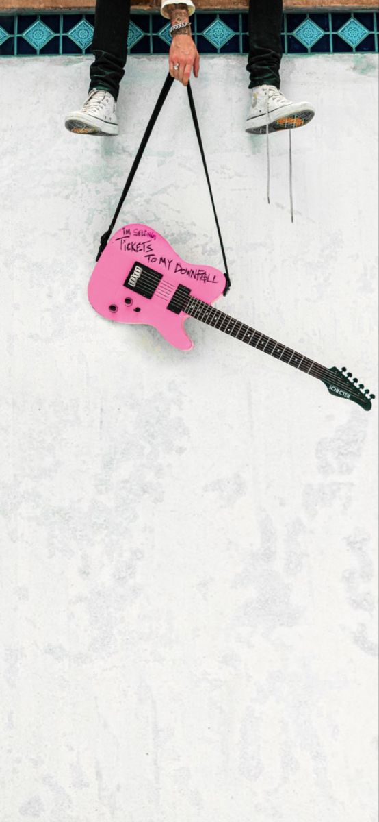 a person sitting on a bench with a pink guitar shaped bag attached to their legs