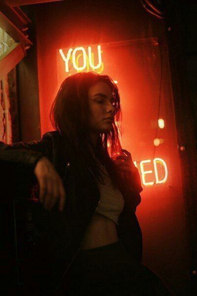 a woman standing in front of a neon sign with the words you spelled on it