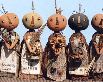 five scarecrow dolls are standing in a row, each with their own face painted on