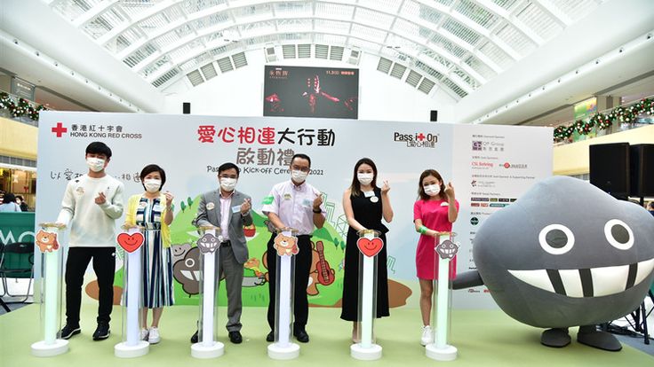 four people are standing in front of some fake objects with faces on them and one person is wearing a face mask