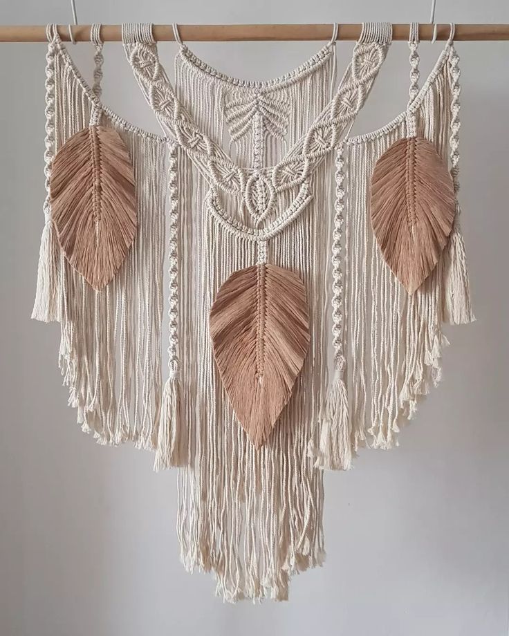 a white wall hanging with three leaf shaped decorations on it's sides and two leaves attached to the side