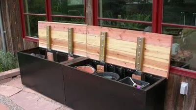 two wooden benches sitting next to each other in front of a red building with windows