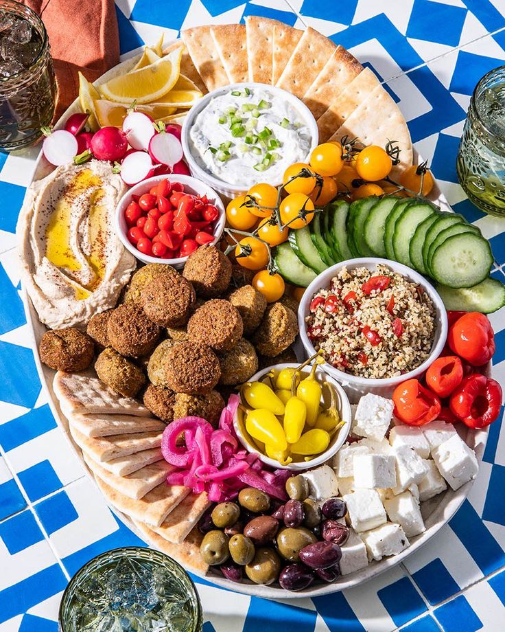 a platter filled with different types of food on top of a blue and white checkered table cloth