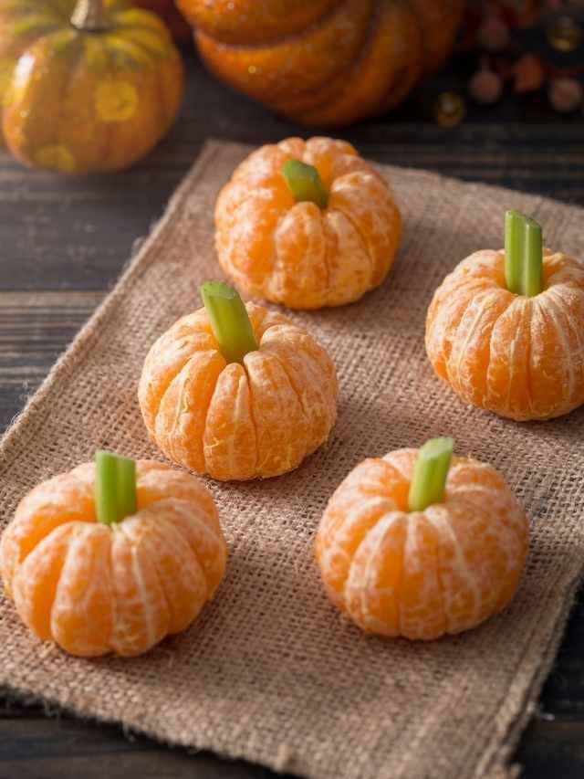 four peeled oranges sitting on top of a burlock next to pumpkins