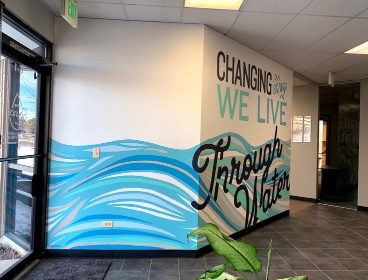 an office with a mural painted on the wall next to a plant in front of it